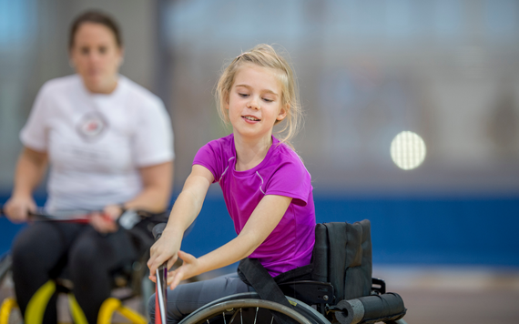 A girl in a wheelchair using a hockey stick