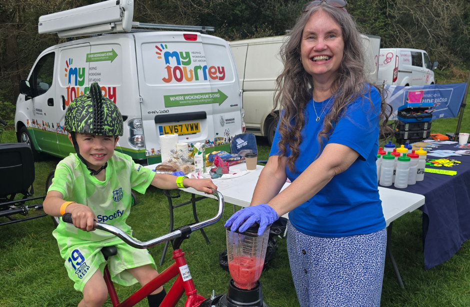 a little boy in a novelty dinosaur bike helmet pedals an exercise bike connected to a smoothie maker