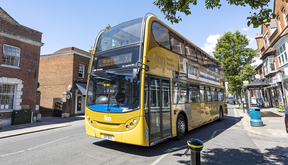 a double decker bus pulls up at a stop on a lovely sunny day