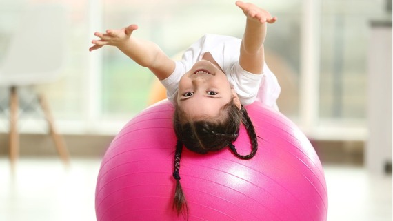 child stretching on a yoga ball
