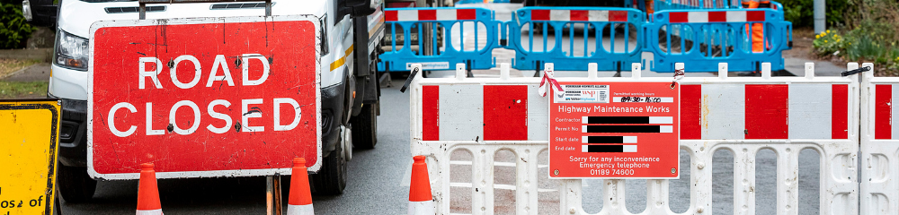 a road closed sign with plastic barriers across a road
