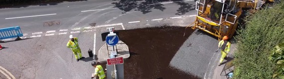 overhead view of workmen laying chippings down on fresh asphalt
