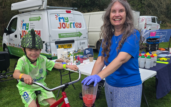 A team member at the Easter bike bonanza along with a child having a go on the smoothie maker