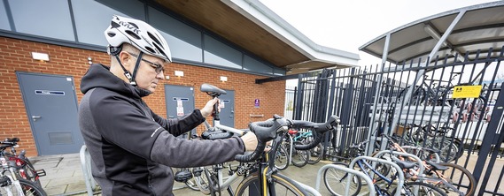 a man lifting a bicycle onto a rack outside Wokingham railway station