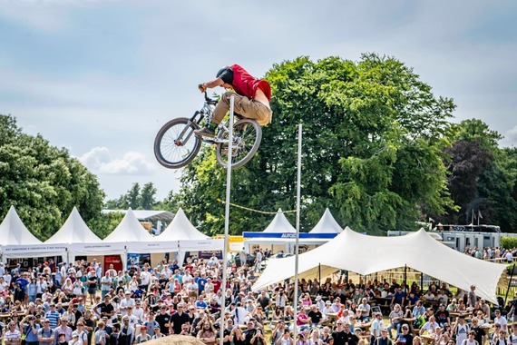 a member of the Fusion Extreme BMX team captured mid-air during a stunt jump at a crowded community fair