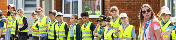 children in high viz vests looking both ways before attempting to cross a road