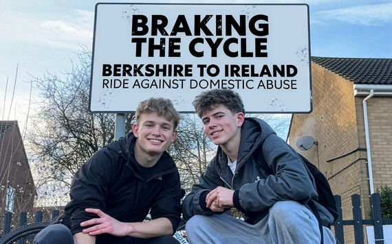 Harley and Noah in front of a sign reading 'Braking the Cycle. Berkshire to Ireland. Ride against domestic abuse'