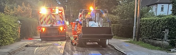 two highways vans with flashing orange lights working on a road near Wokingham