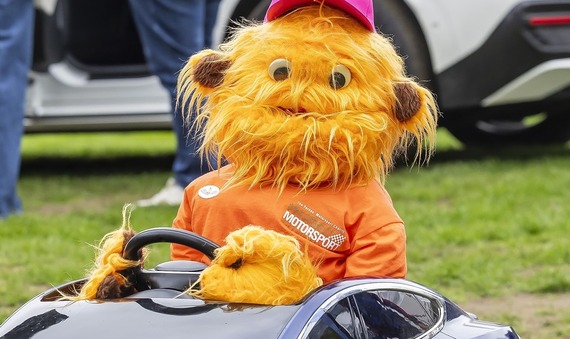 close-up on a cute monster puppet driving a model of an electric car