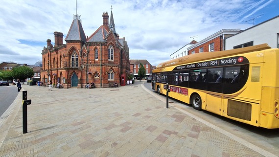 Ultra-wide shot of a bus driving past Wokingham town hall with the pedestrianised market place in the foreground