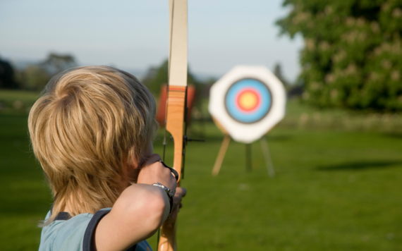 A boy using a bow and arrow to hit a target 