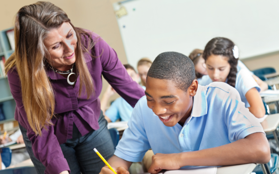 A teacher supporting a young person writing at school