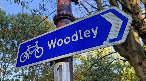A sign attached to a lamppost showing a cycle route to Woodley from Palmer Park