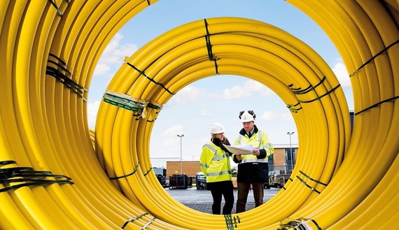 view through a big coil of plastic yellow gas pipes with gas engineers looking at paperwork