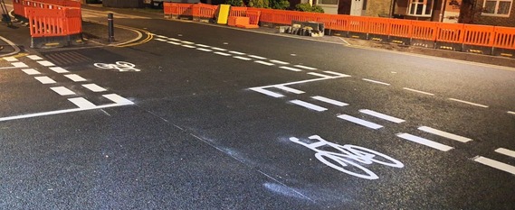 Close up of a bike lane crossing the mouth of a side junction, where cyclists and pedestrians have priority over motorists