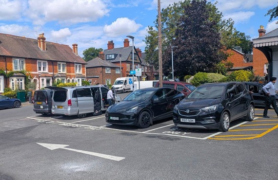 a line of cars parked in a small row of spaces in front of Twyford railway station
