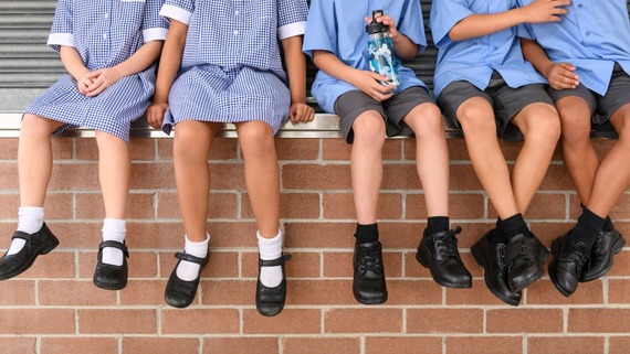 photo of legs of schoolchildren who are sitting on a wall