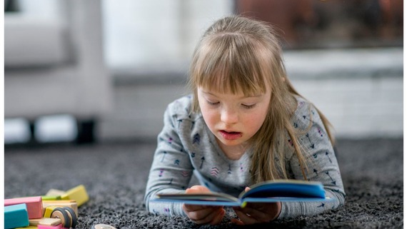 image of a child lying on the floor reading a book