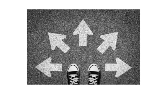 image of someone's feet as they stand with many arrows in front of them on the pavement, going in different directions