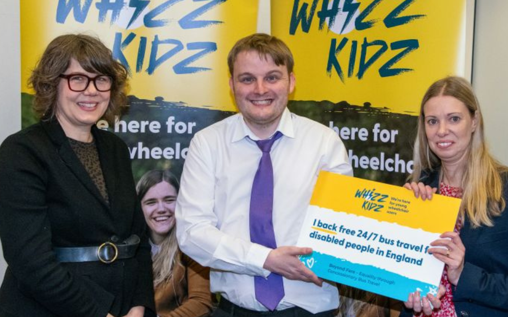 Three people stood in front of 'whizz kids' signs