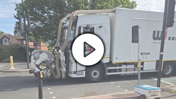 a large road maintenance vehicle with a water blasting attachment at the front, with a play button superimposed