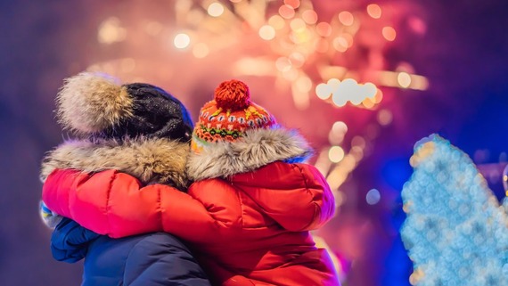 image of parent holding a child up to watch a fireworks display