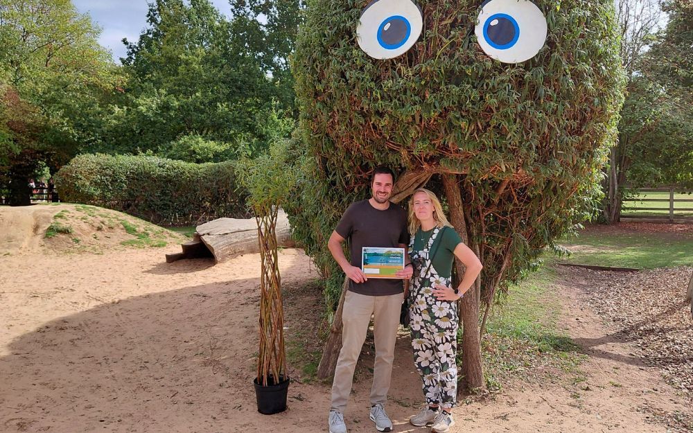 Winner beneath Willowby at Dinton Pastures Country Park holding competition prize certificate.