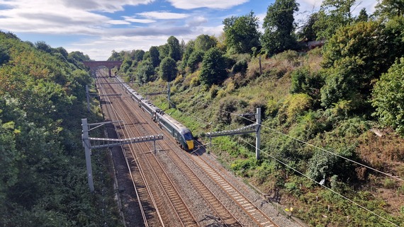 A GWR train on the railway at Sonning Cutting, with earth banks either side, viewed from Warren Road bridge in Woodley