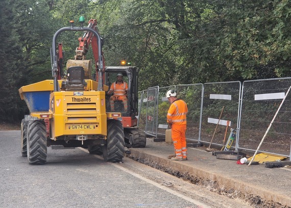a Thames Water worker in a digger excavates a trench in Barkham Road for new pipes to be laid