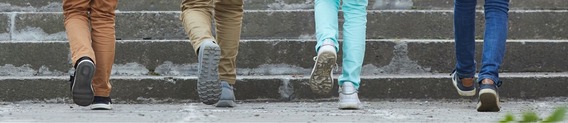 close-up on four childrens' feet in trainers, walking up an outdoor flight of stairs