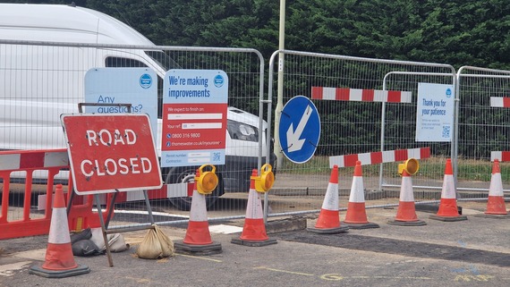 close up on a closed road with metal fencing and closure signs as well as Thames Water's logo