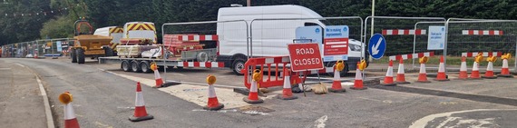 a Thames Water road closure at a mini roundabout with mesh fencing and signs