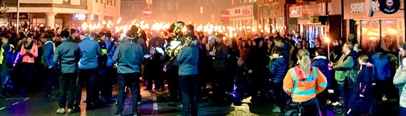 large crowd gathering with flaming torches in Wokingham town centre, preparing to parade through the street