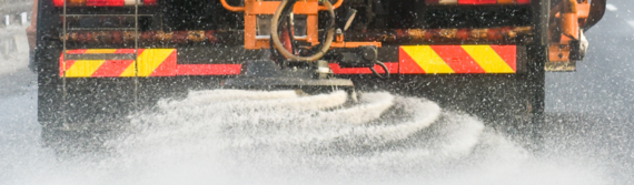 close up on the back of a gritter lorry spraying grit all over the road