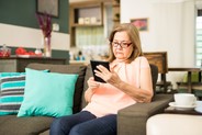 Lady in her home using a tablet on the sofa