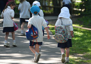 Two Reception aged children in school uniform walking into a school building