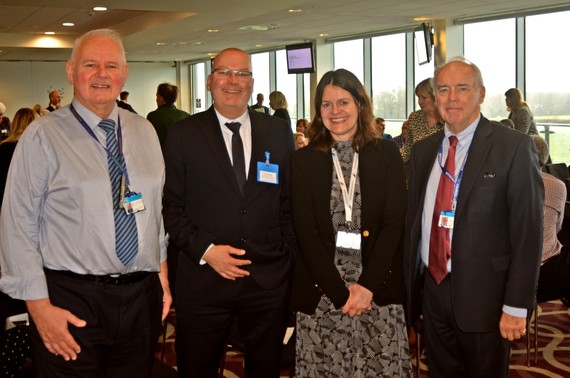 Three men and a woman in smart business dress standing in a line at a recent multi academy trust engagement event
