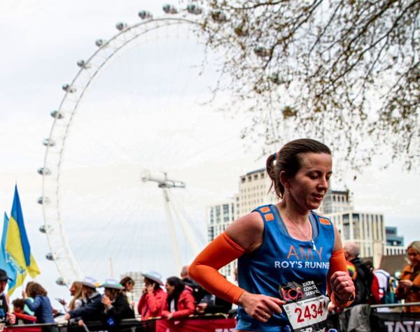An image of a woman running past the London Eye during the London Marathon