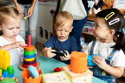 Picture of three toddlers playing with toys around a turquoise table