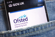 Mobile phone in a jeans pocket showing the Ofsted logo on screen