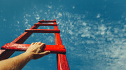 A red ladder rising into the blue cloudy sky, with hands climbing up it