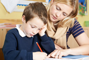 A photograph of a child working with a teacher at a desk 
