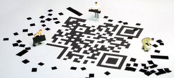 Small plastic figures piecing together a QR code on the floor
