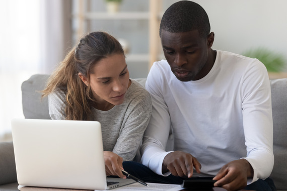 Young couple looking at paperwork on a table with a laptop