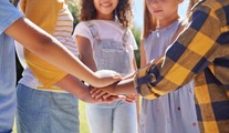 children standing in a circle with their hands in the centre