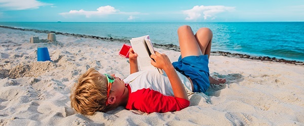 boy reads on beach