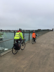 Adult and child in high visibility clothing cycling across a bridge