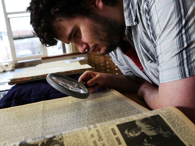 A man looking at a document through a magnifying glass
