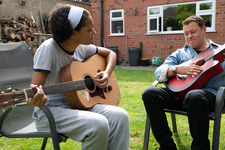 Image of a young woman and man playing guitar