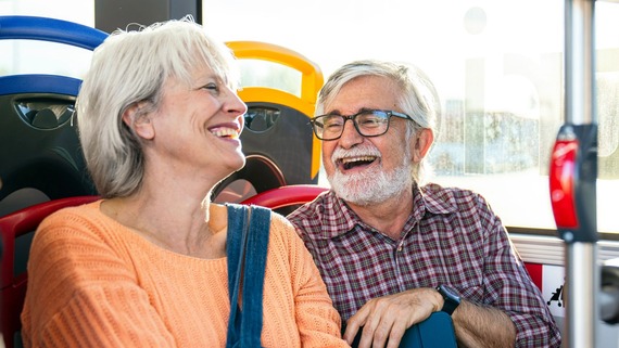 Two elderly individuals laughing on the bus.